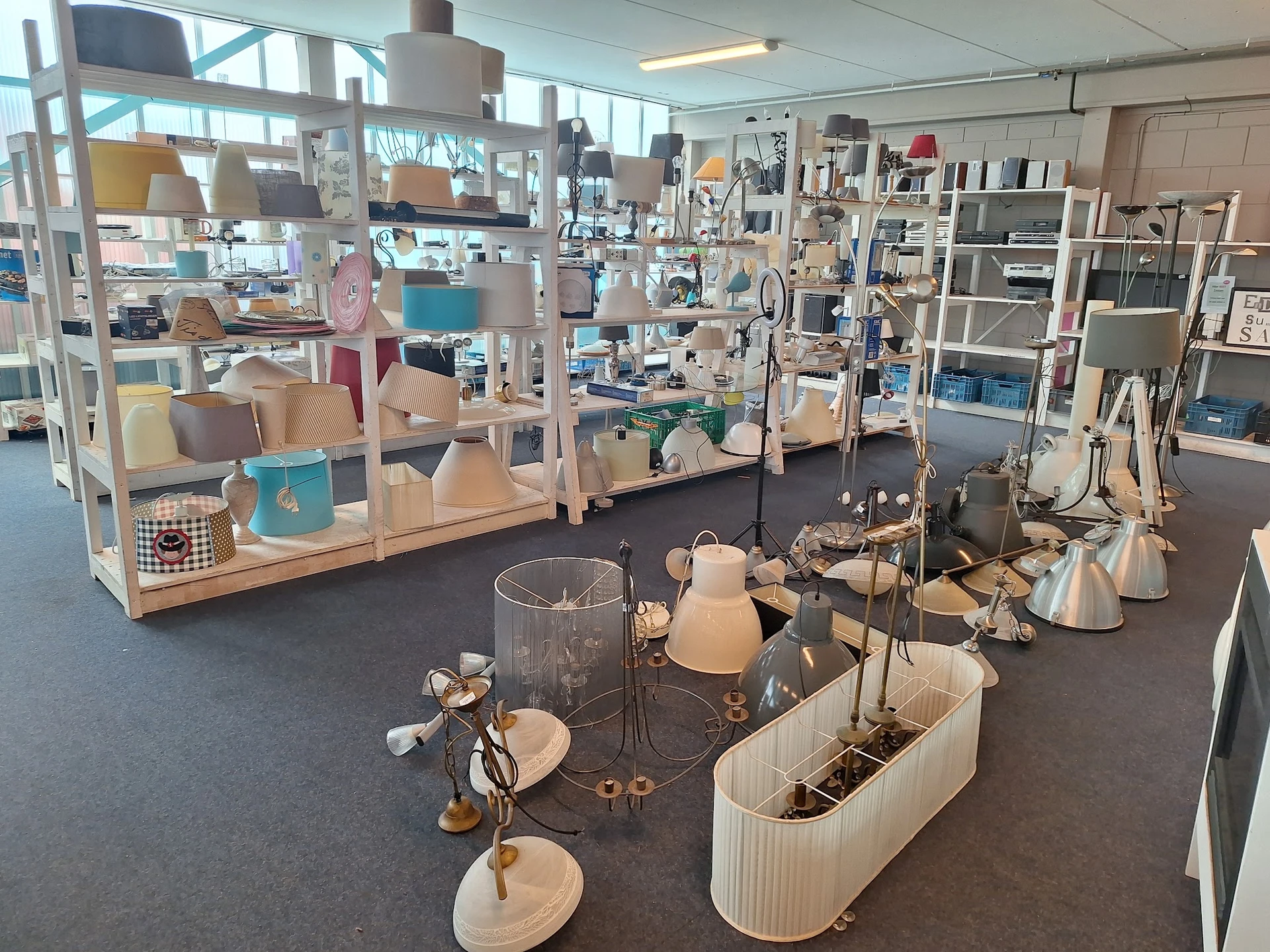 Winkelvloer met uitgestalde huishoudelijke artikelen, lampen, servies en decoratieve items op tafels en stellingen
