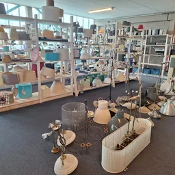 Winkelvloer met uitgestalde huishoudelijke artikelen, lampen, servies en decoratieve items op tafels en stellingen