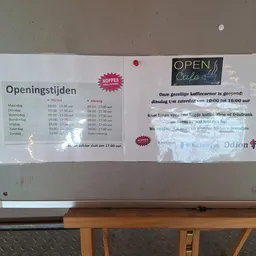 Openingstijden en bedrijfsinformatie poster van kringloopwinkel aan muur