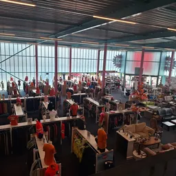 Ruim winkelinterieur met kledingrekken, mannequins en winkelassortiment onder glazen dak