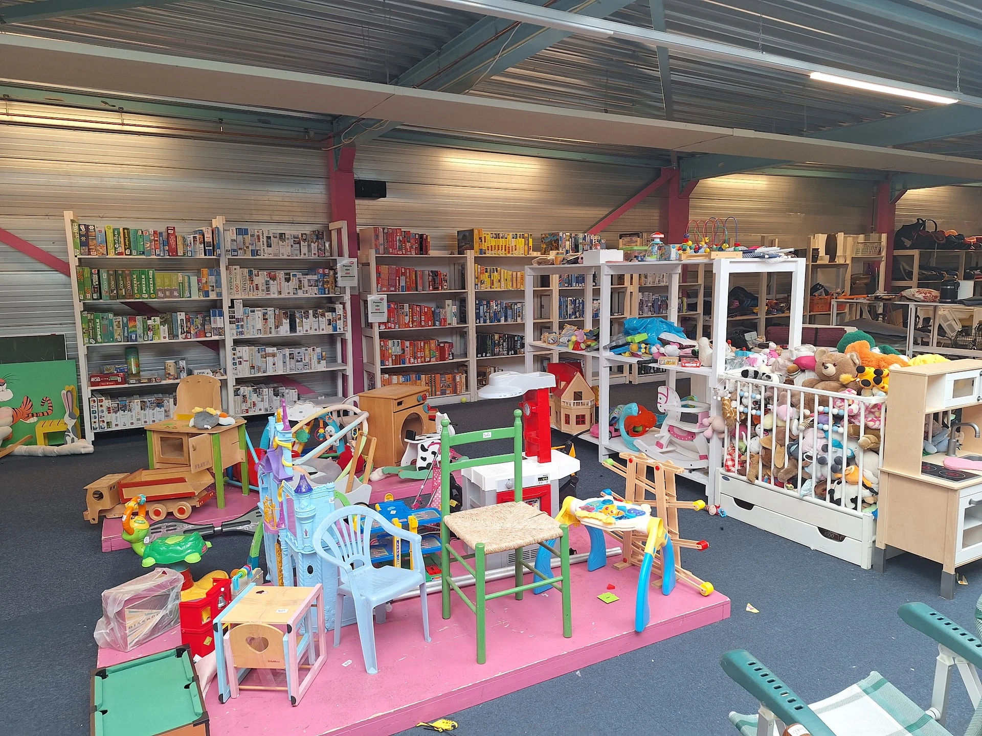 Speelhoek met kinderspeelgoed en kleurige meubels, met boekenkasten op de achtergrond