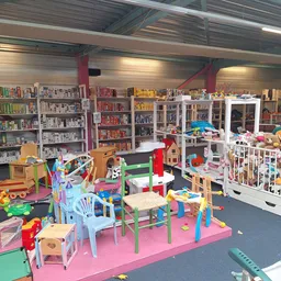 Speelhoek met kinderspeelgoed en kleurige meubels, met boekenkasten op de achtergrond