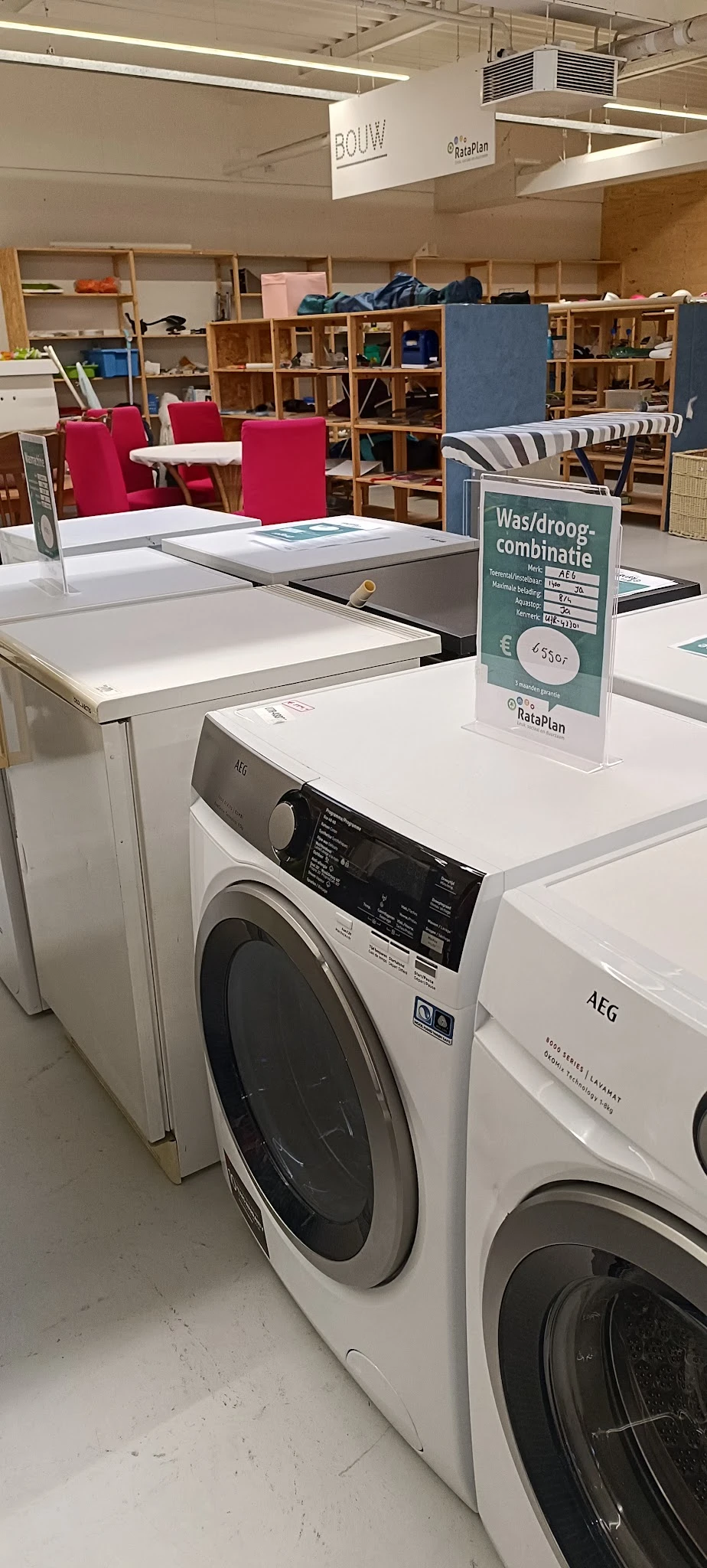 Uitstalling van witgoedapparatuur in kringloopwinkel met wasmachines en drogers