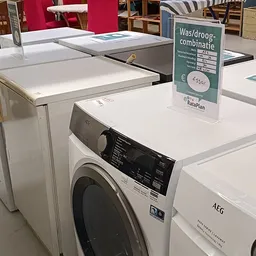 Uitstalling van witgoedapparatuur in kringloopwinkel met wasmachines en drogers