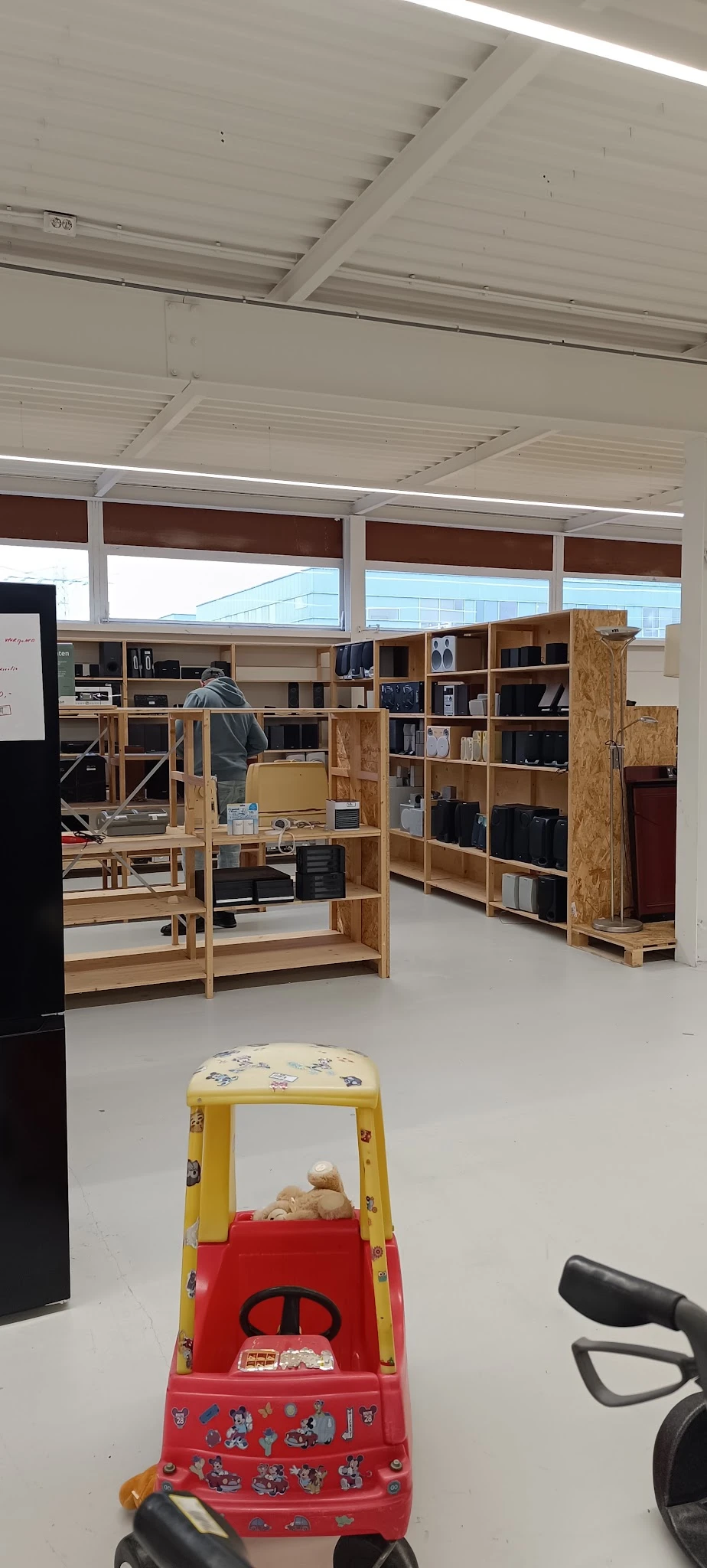Houten stellingen en kasten met boeken, elektra en huishoudelijke artikelen in een kringloopwinkel