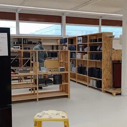 Houten stellingen en kasten met boeken, elektra en huishoudelijke artikelen in een kringloopwinkel