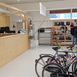 Winkelinterieur met houten balie, houten stellingen met electronica, zwarte metalen rekken en fietsen op de vloer
