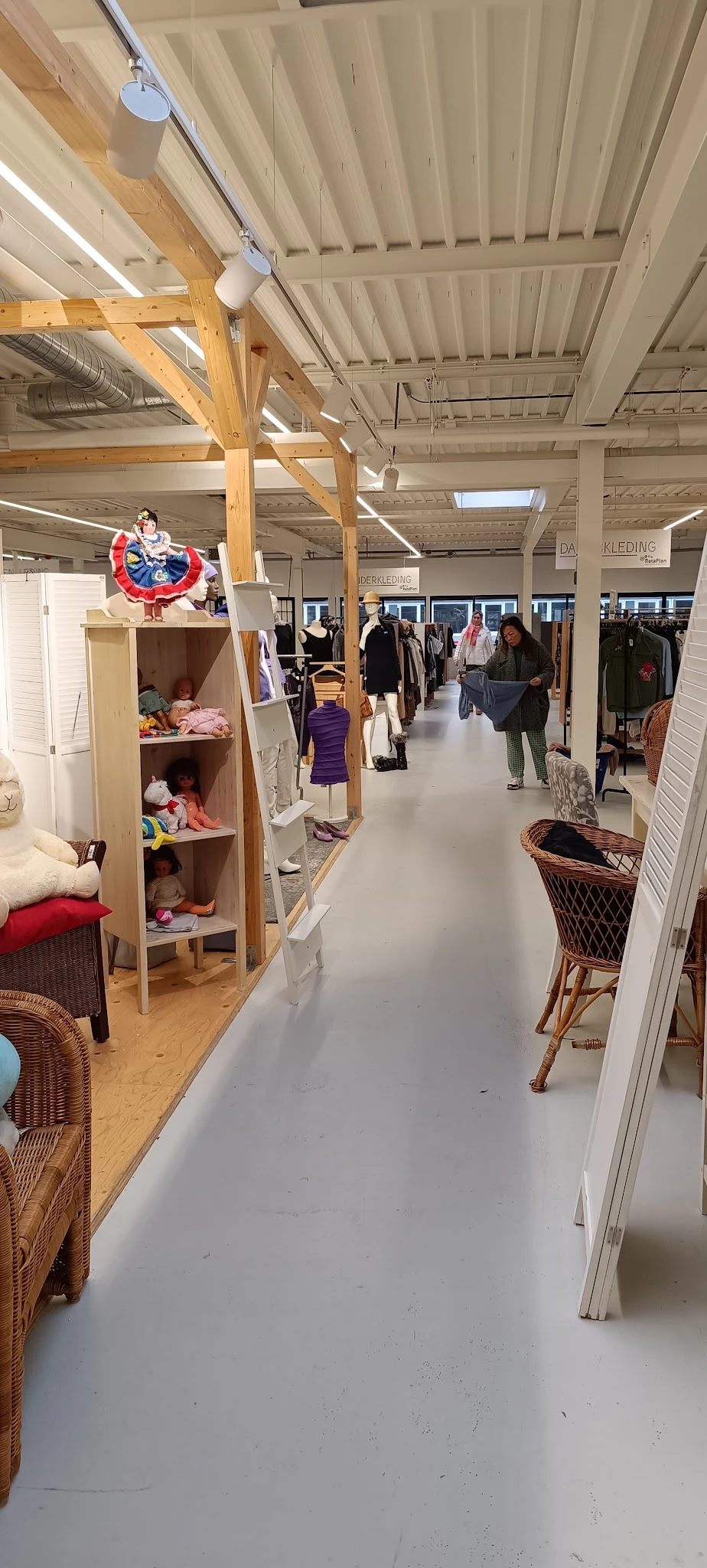 Winkelvloer van kringloopwinkel met stellingen, kleding, meubilair en decoraties