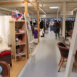 Winkelvloer van kringloopwinkel met stellingen, kleding, meubilair en decoraties