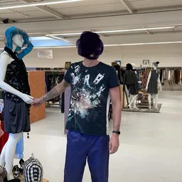 Mannequin met blauwe pruik en pop-up klant in grijs t-shirt in kringloopwinkel met kledingrekken op achtergrond