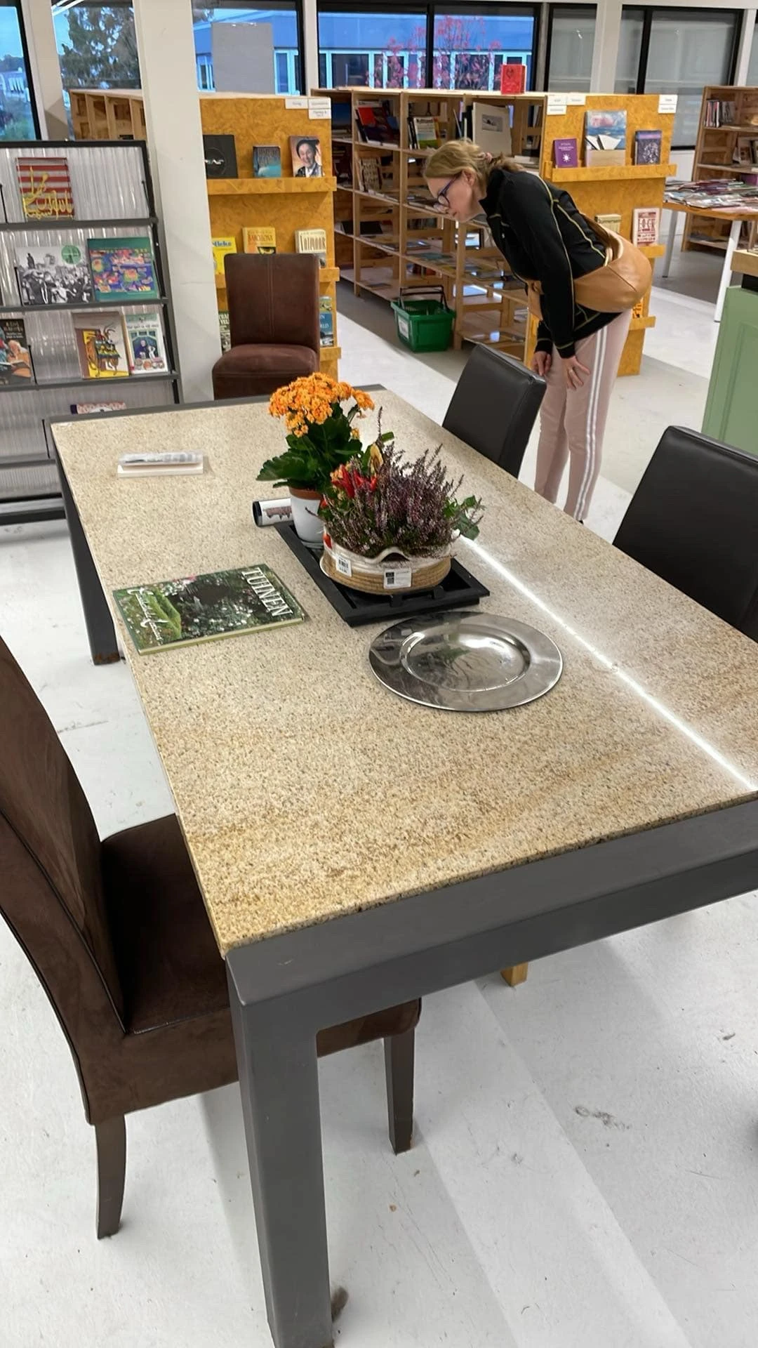 Betonnen toonbank met bloemen, decoratieve items en een metalen schaal in een kringloopwinkel