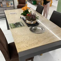 Betonnen toonbank met bloemen, decoratieve items en een metalen schaal in een kringloopwinkel