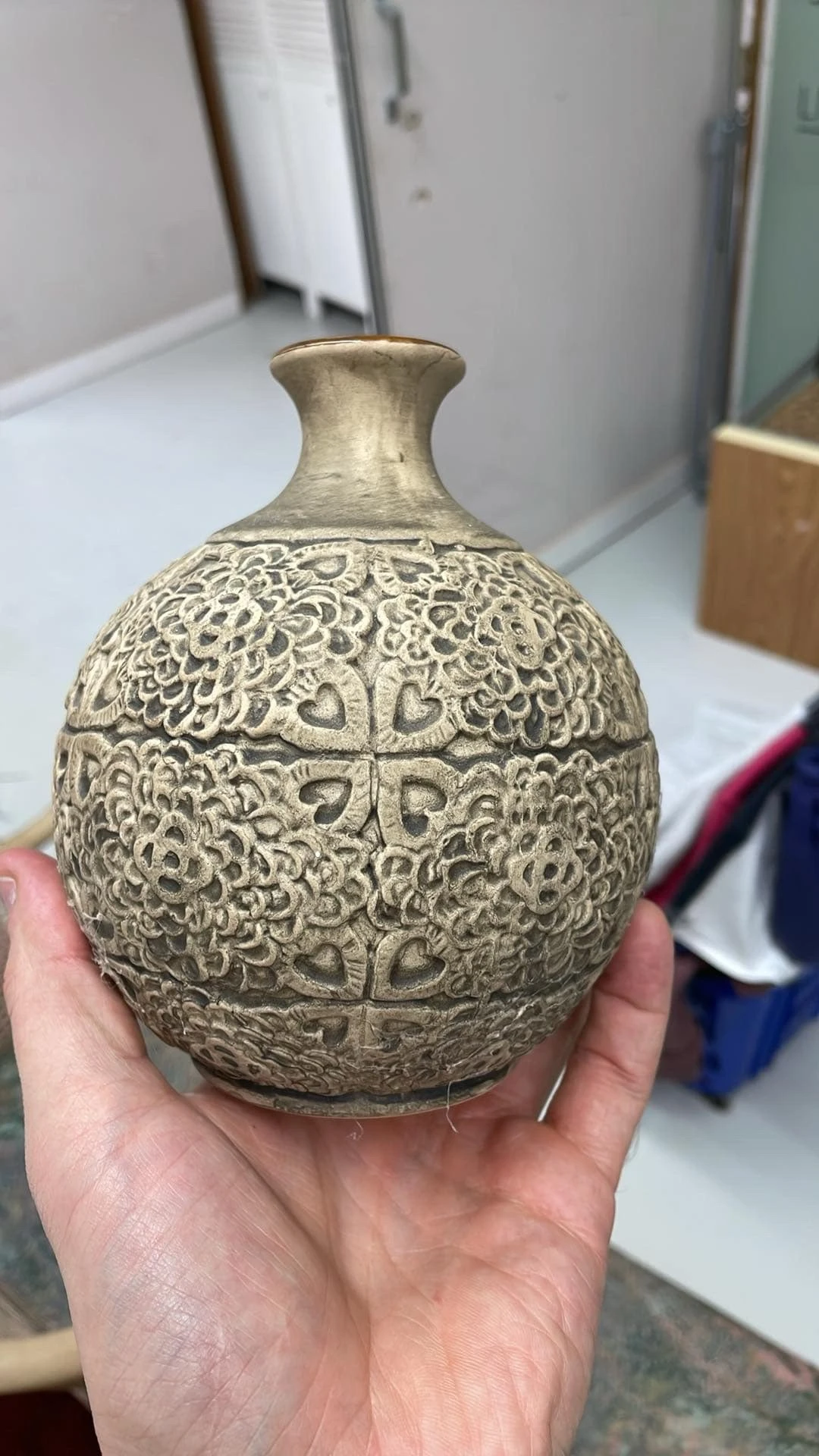 Close-up van een decoratief metalen object met ingewikkeld ornamentaal patroon, gehouden in een hand
