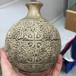 Close-up van een decoratief metalen object met ingewikkeld ornamentaal patroon, gehouden in een hand
