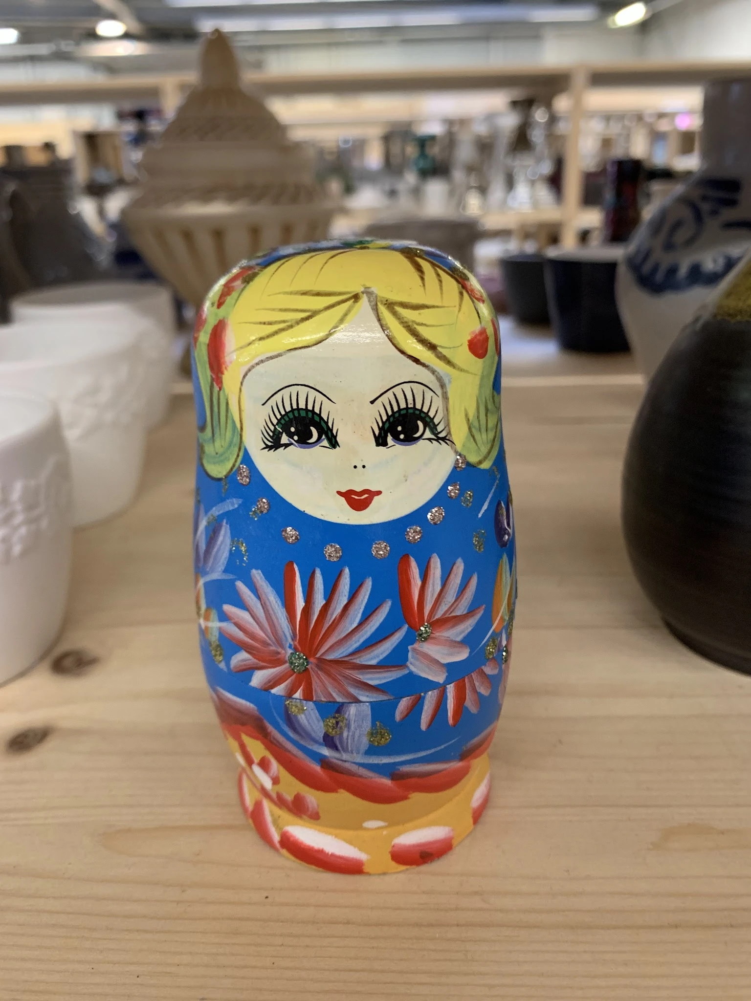Russische matroesjka-pop met geel haar, blauwe jurk en bloemenpatroon
