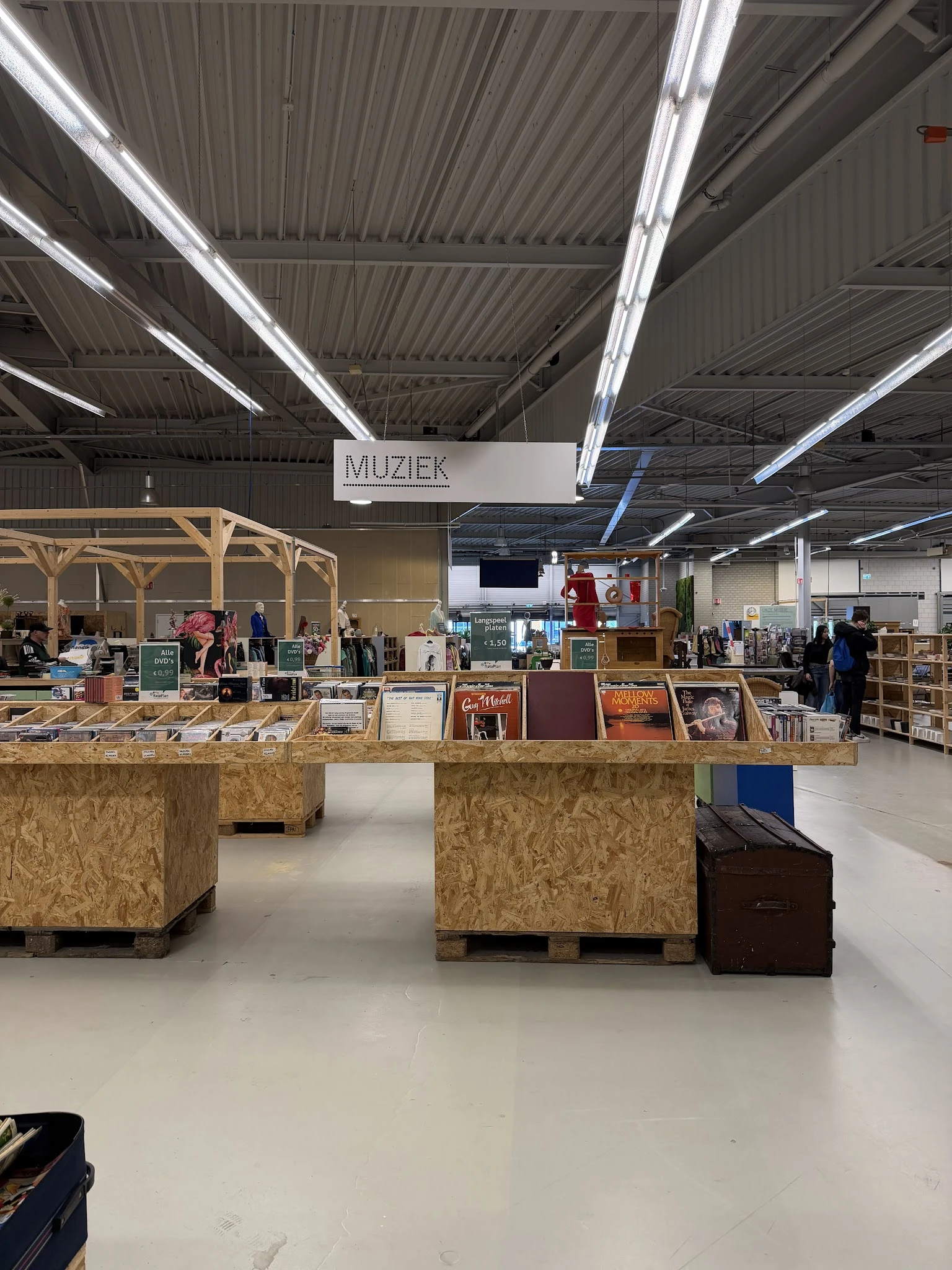 Winkelinterieur met houten toonbanken, stellingen en diverse tweedehands artikelen onder 'MUZIEK' afdeling