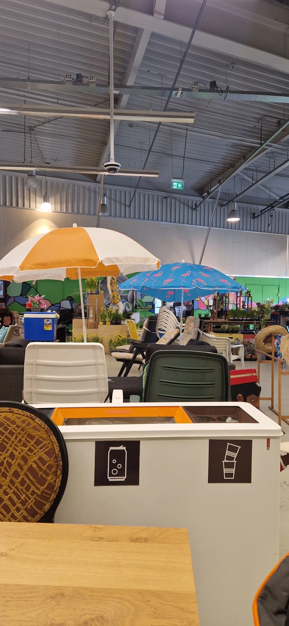 Winkelinterieur met stoelen, parasols en tuinmeubels uitgestald onder groene muur