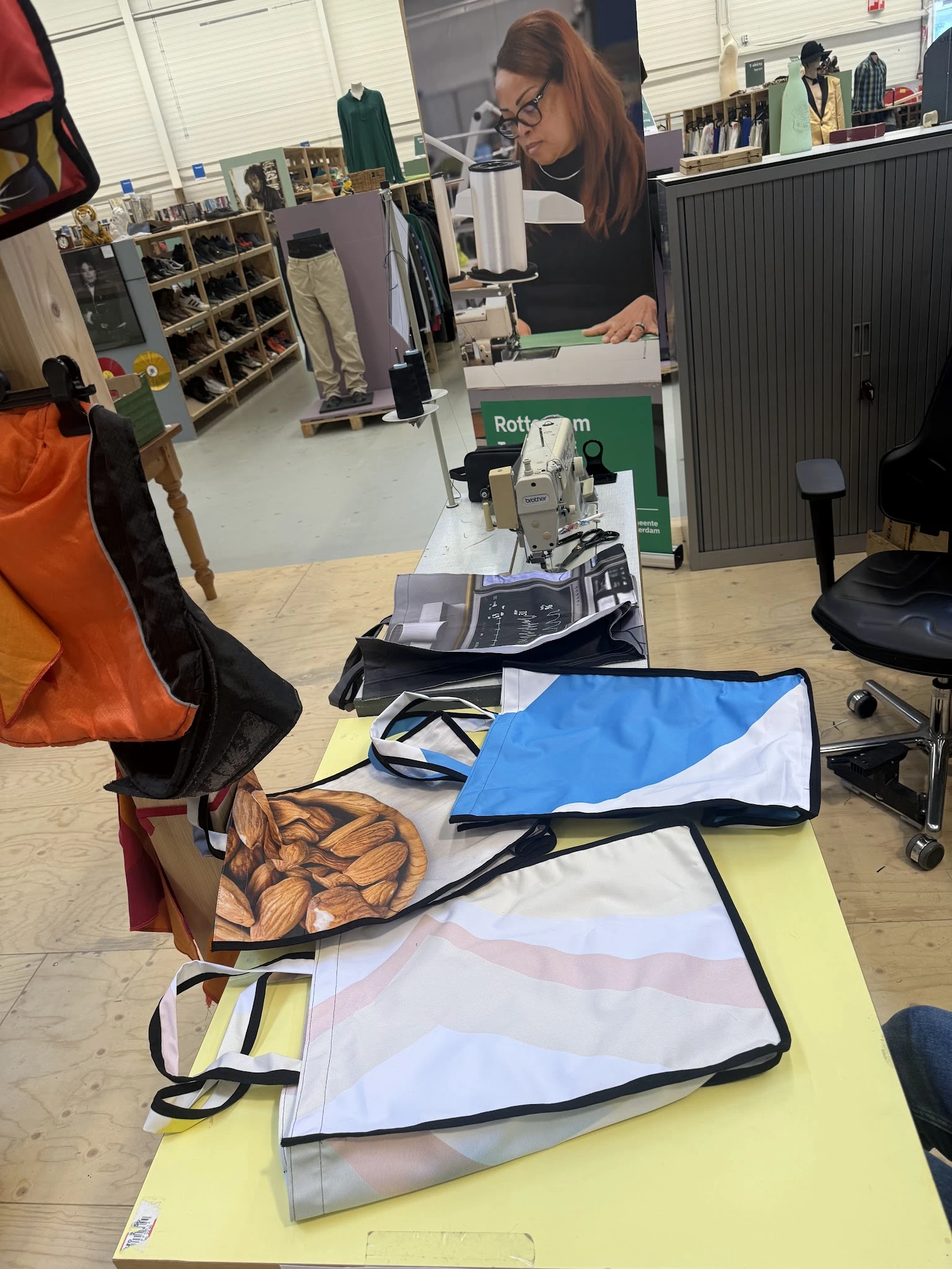 Diverse tweedehandsartikelen uitgestald op de winkelplank, waaronder kleding, tassen en andere spullen