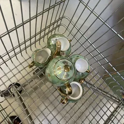 Vintage groene porseleinen theeservies met gouden hengsels in winkelwagen