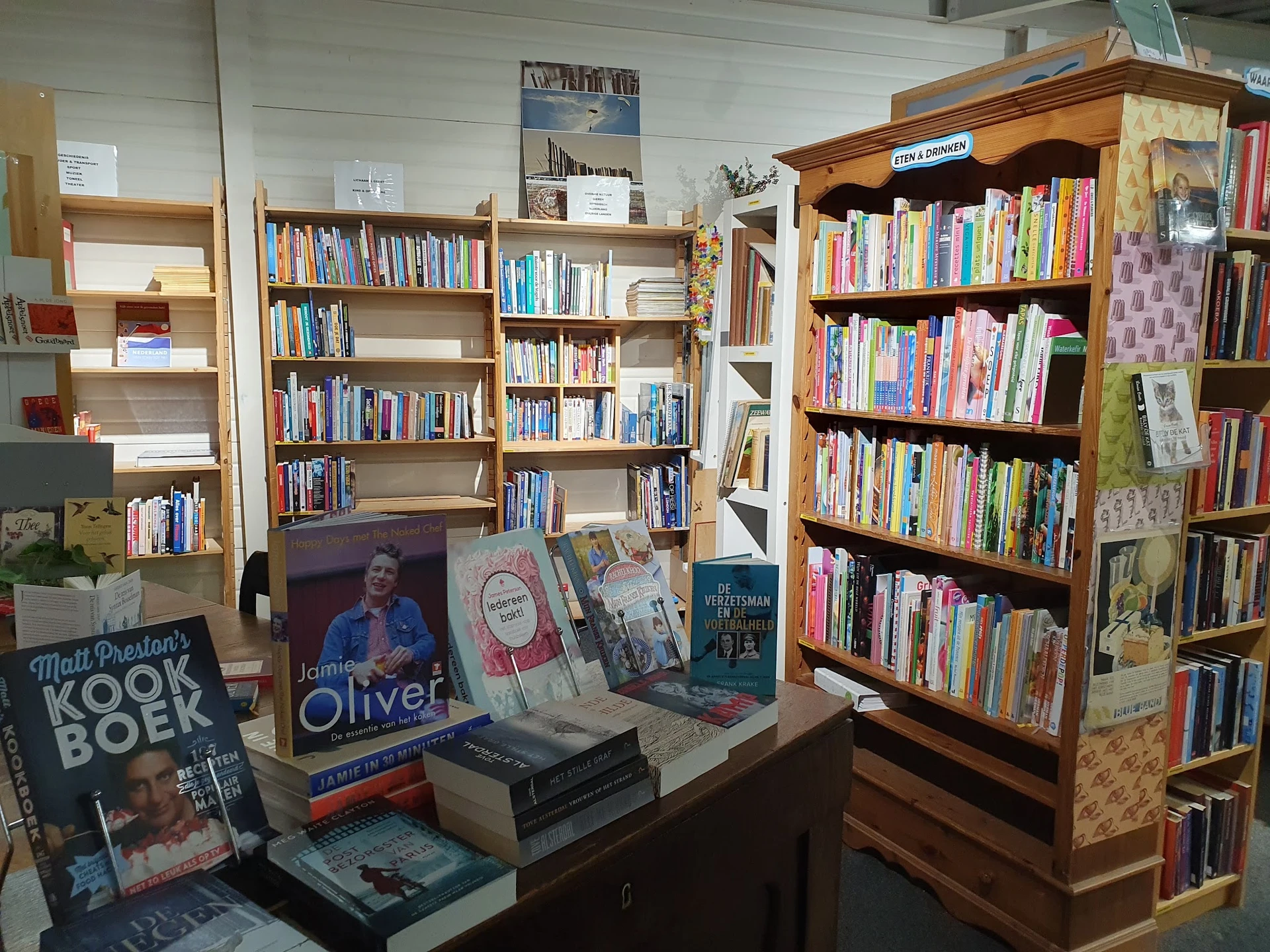Boekenkasten met tweedehands boeken en display met uitgestalde boeken op een tafel in de winkel