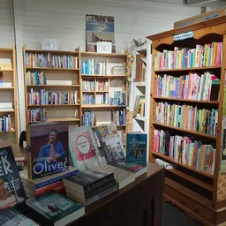 Boekenkasten met tweedehands boeken en display met uitgestalde boeken op een tafel in de winkel