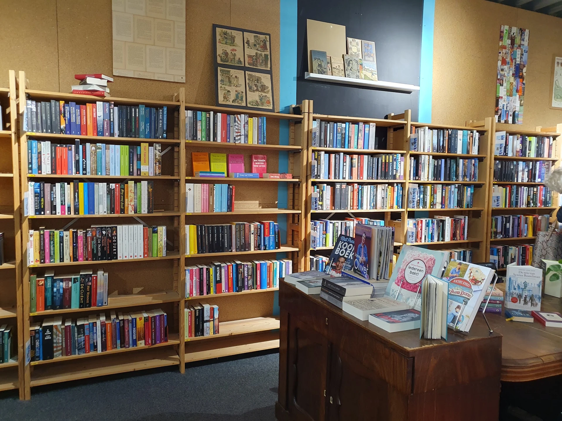 Houten boekenkasten gevuld met boeken en dvd's, met een bruine balie met uitgangsmaterialen op de voorgrond