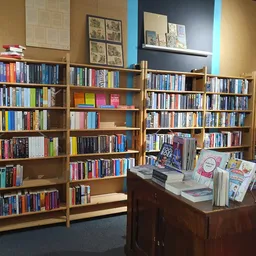 Houten boekenkasten gevuld met boeken en dvd's, met een bruine balie met uitgangsmaterialen op de voorgrond