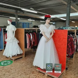 Kledingrekken met jurken, jassen en andere tweedehands kleding in de winkel, met etalagepoppen in witte jurken