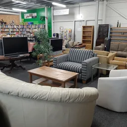 Winkelvloer met zithoeken, banken, fauteuils, salontafel, computers en boekenkasten op de achtergrond