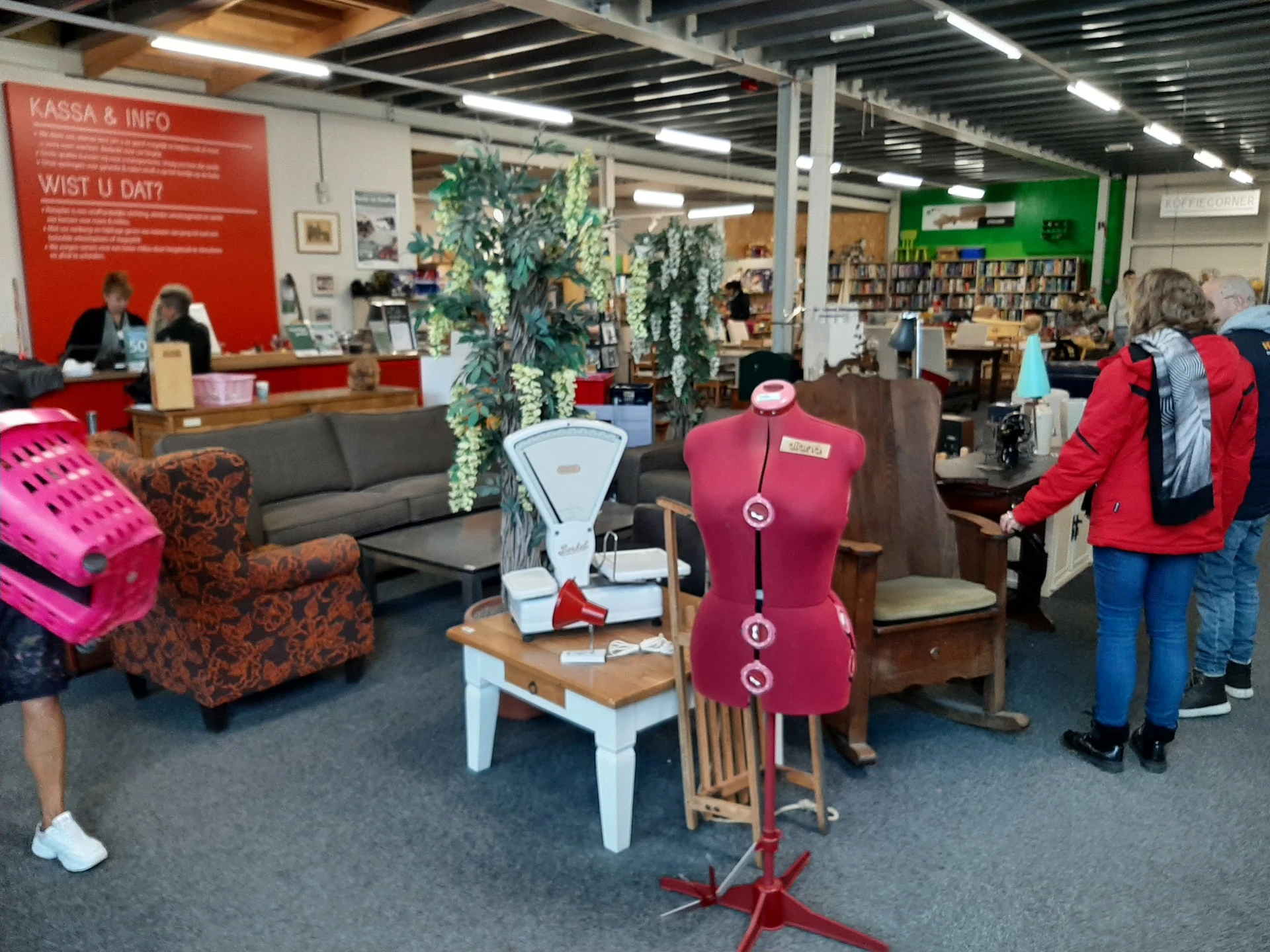 Winkelvloer met diverse meubels, stoelen en decoratieve items, bezoekers in de winkel