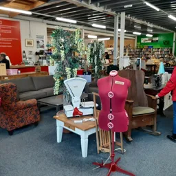 Winkelvloer met diverse meubels, stoelen en decoratieve items, bezoekers in de winkel