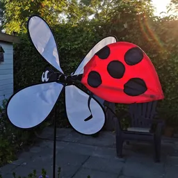 Decoratief tuinspeelgoed: rode lieveheersbeestje met zwarte stippen en blauwe windmotor
