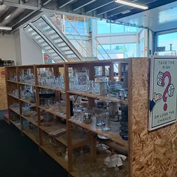 Glazen vitrinekasten met diverse glaswerk en huishoudelijke artikelen in een kringloopwinkel