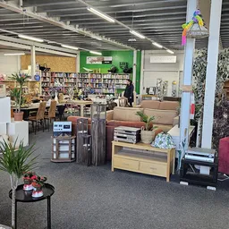 Winkelvloer van kringloopwinkel met boekenkasten, meubels, huisplanten en diverse tweedehands artikelen