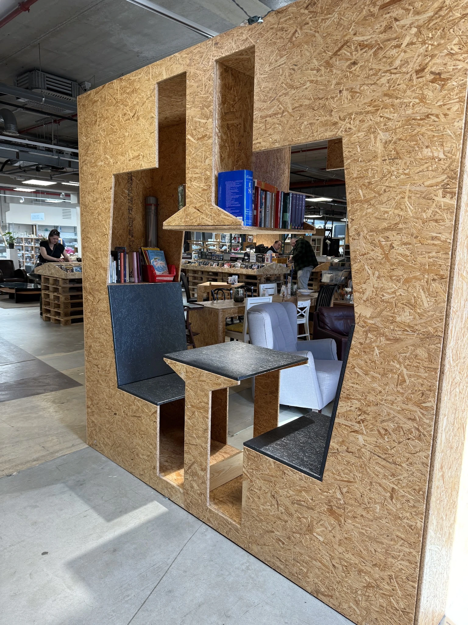 Interieur van kringloopwinkel met kurken scheidingswanden en zithoek met tafel en stoelen