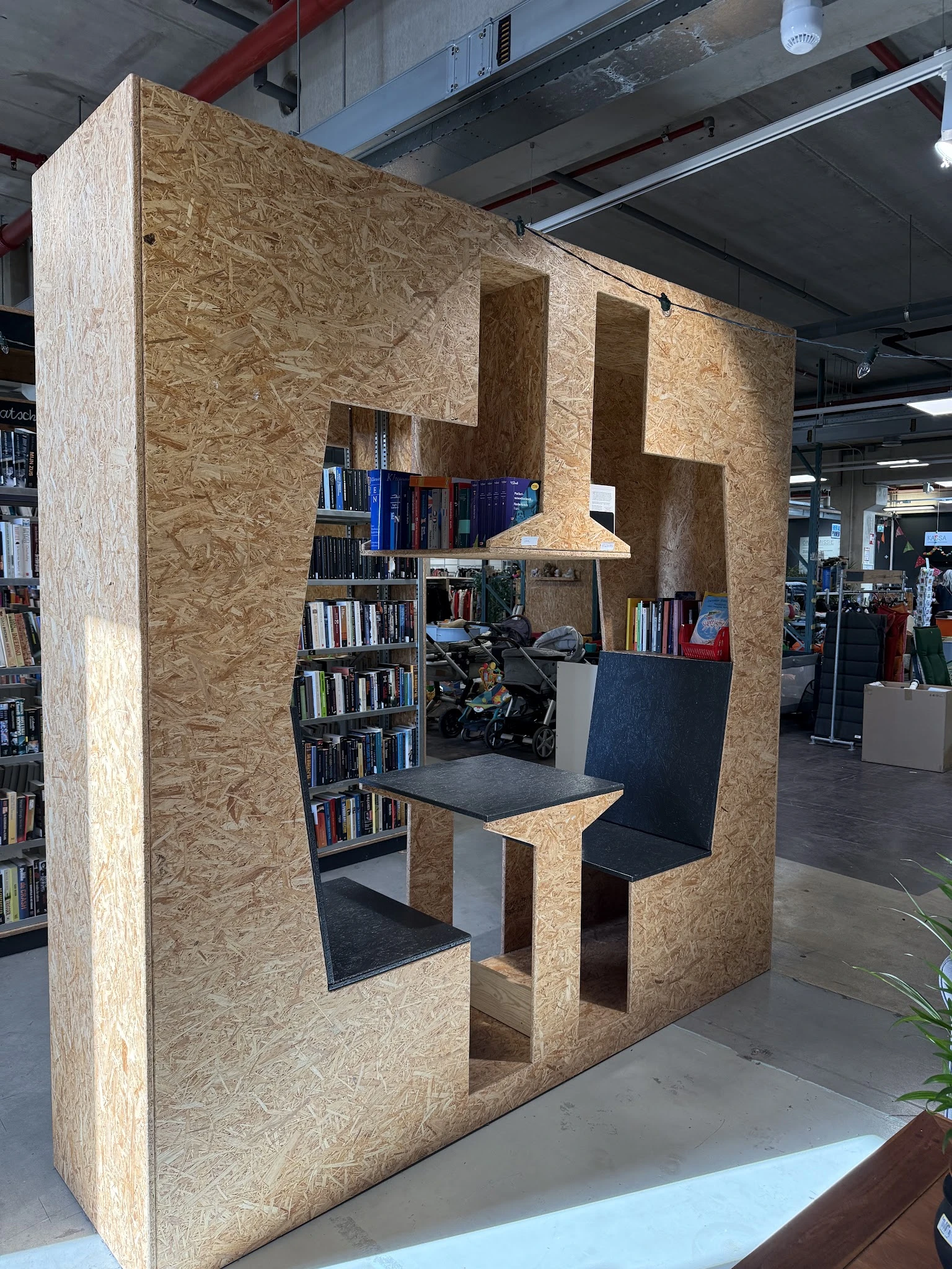 Inrichting met boeken in kasten en een zwarte tafel in een winkelruimte met een motor op de achtergrond