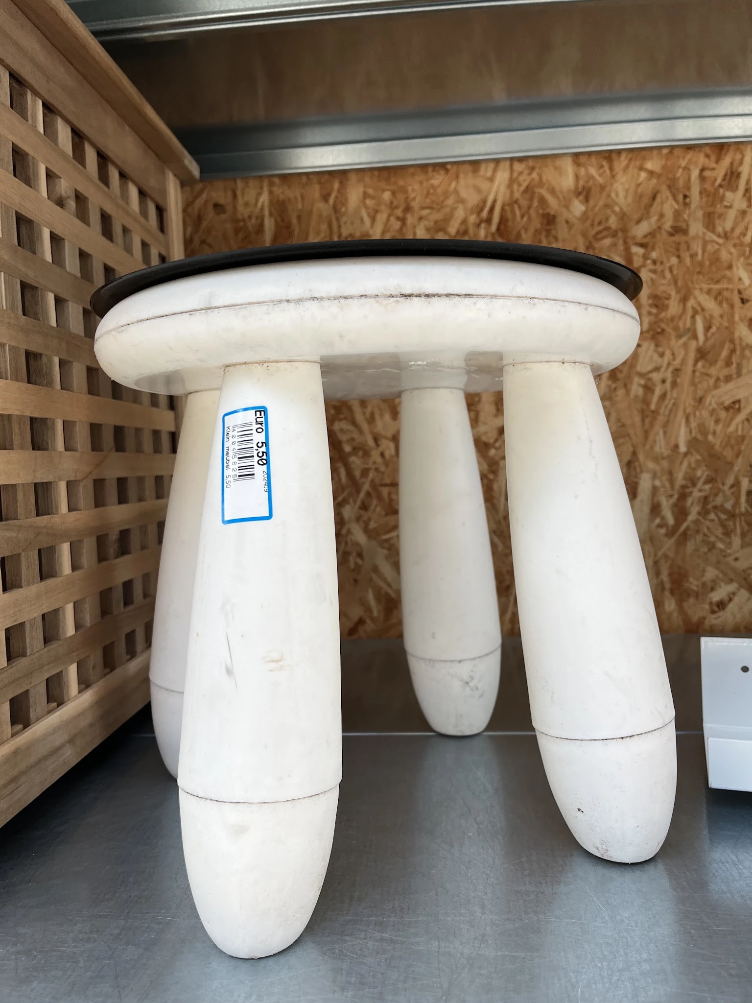 Witte kruk of tafelblad met drie poten en zwart rand, voorzien van winkelsticker