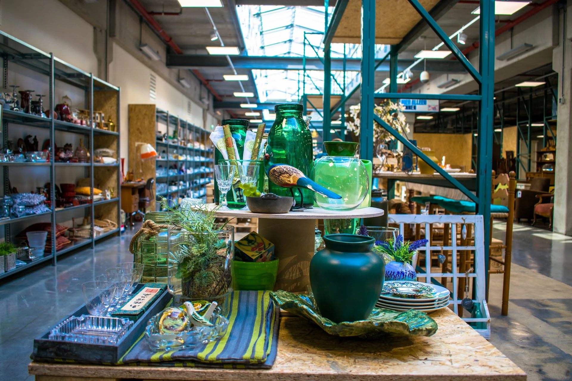 Uitgestalde decoratieve artikelen: groene glazen vazen, flessen en plantenpotten op een display tafel in de winkel