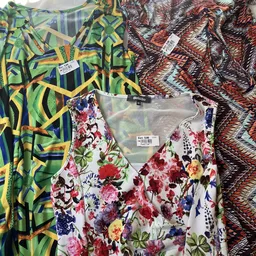 Rekken met tweedehands kleding met verschillende patronen en prints, waaronder bloemendessin en geometrische patronen