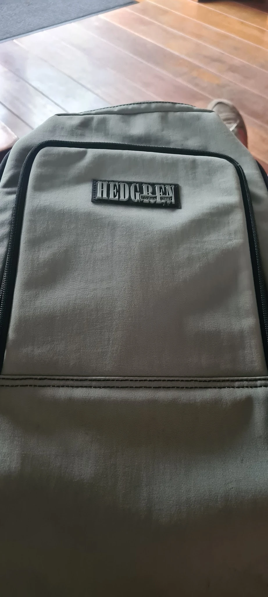 Grijze stof tas of rugzak met rits en label, close-up van de voorkant