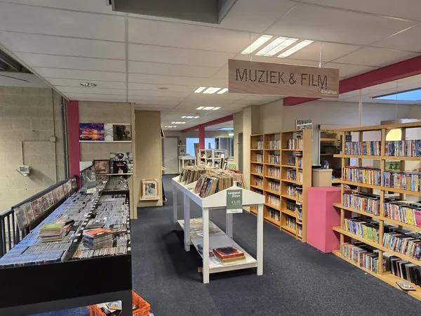 Afdeling Muziek & Film in kringloopwinkel met boekenkasten, cd- en dvd-rekken, en uitgestalde media