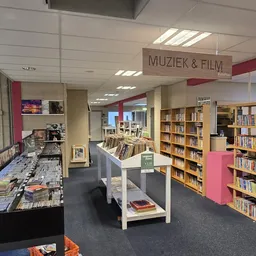 Afdeling Muziek & Film in kringloopwinkel met boekenkasten, cd- en dvd-rekken, en uitgestalde media
