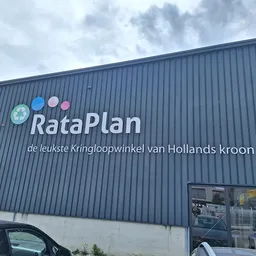 Gevel van kringloopwinkel RataPlan met logo en winkelnaam op grijze golfplaten wand