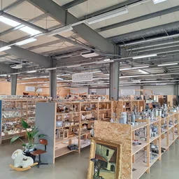 Ruime winkelvloer met houten stellingen en kasten vol tweedehandsartikelen, industrieel plafond met verlichting