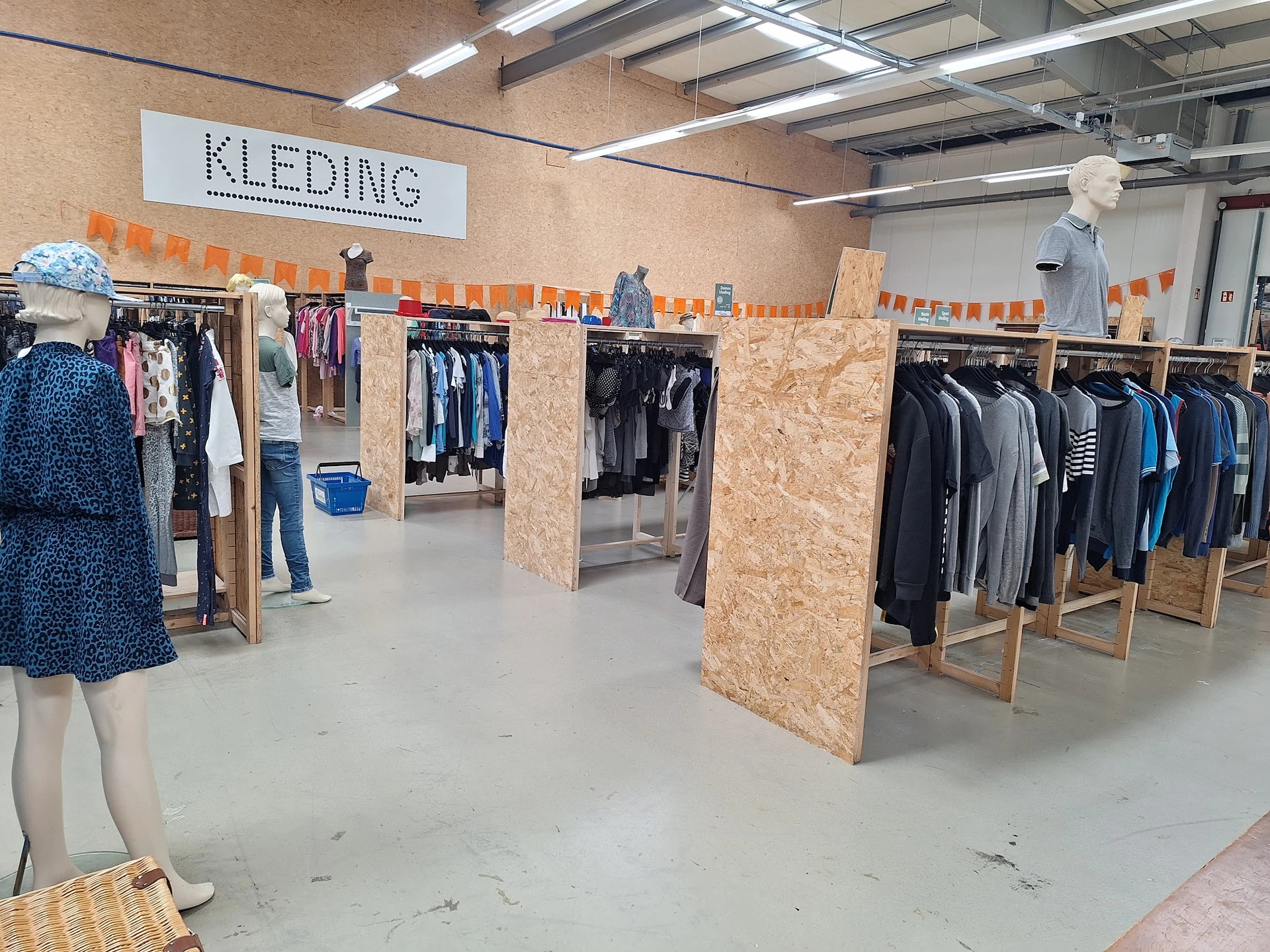 Winkelvloer van kledingafdeling met kledingrekken, mannequin en oranje markeringen aan plafond