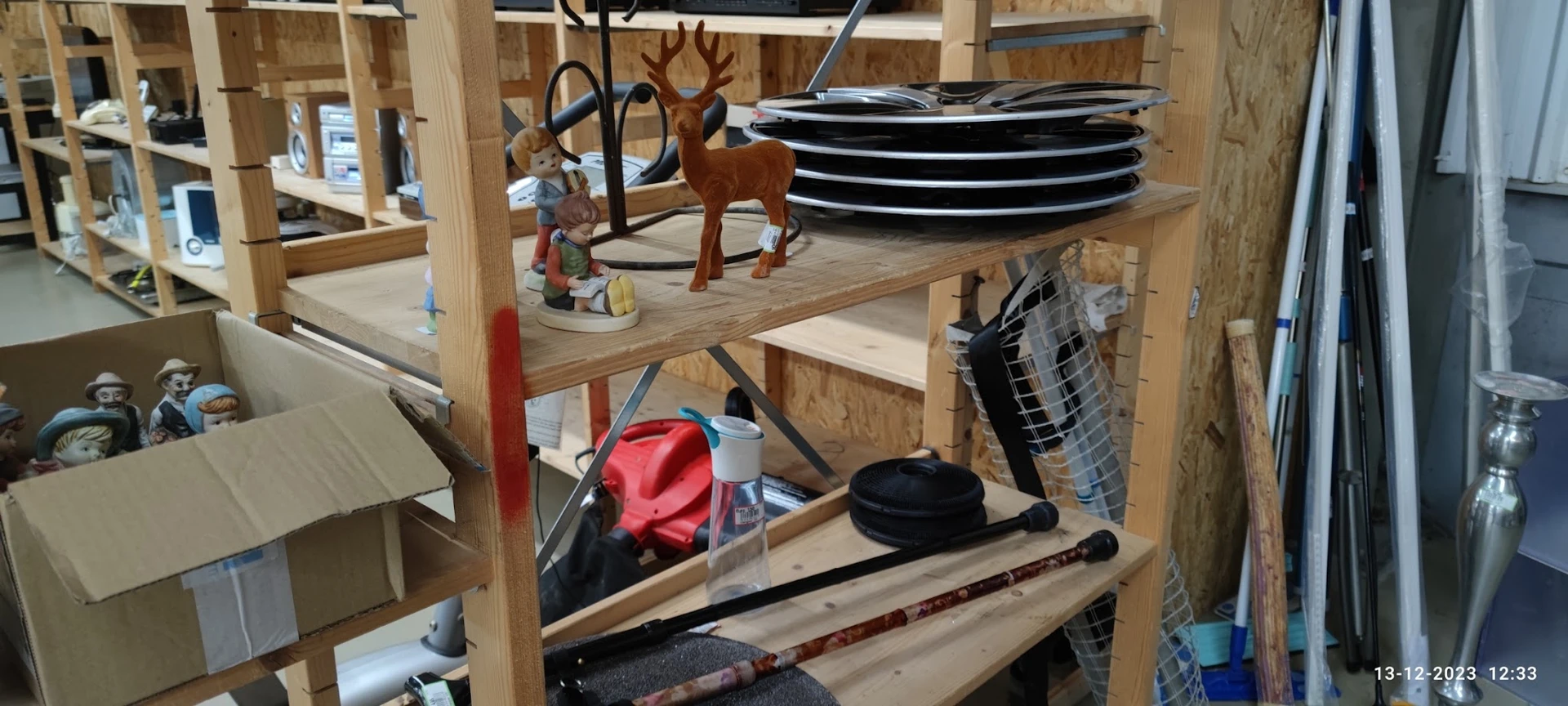 Houten stellingkast met diverse tweedehands spullen zoals borden, decoraties en sportartikelen