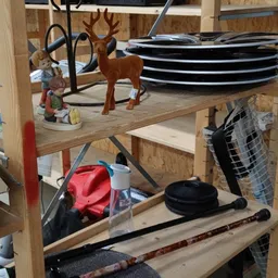 Houten stellingkast met diverse tweedehands spullen zoals borden, decoraties en sportartikelen