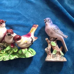 Twee porseleinen vogelbeeldjes op blauwe stof