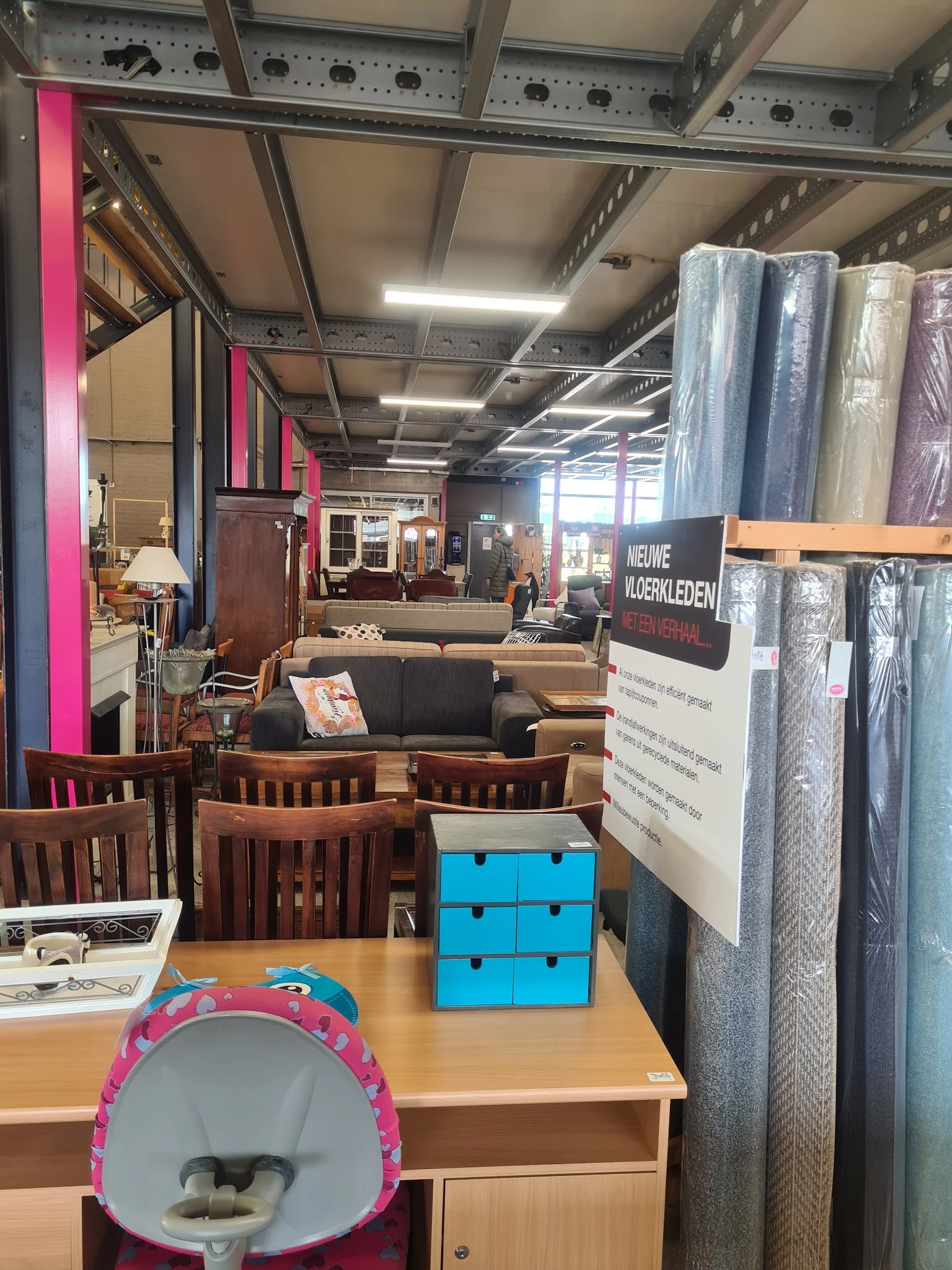Winkelvloer met houten stoelen, bank, kasten en verschillende meubelstukken op uitgestalde plekken