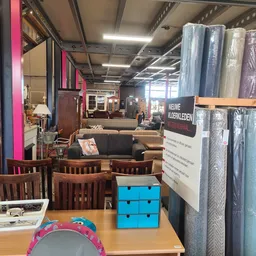 Winkelvloer met houten stoelen, bank, kasten en verschillende meubelstukken op uitgestalde plekken